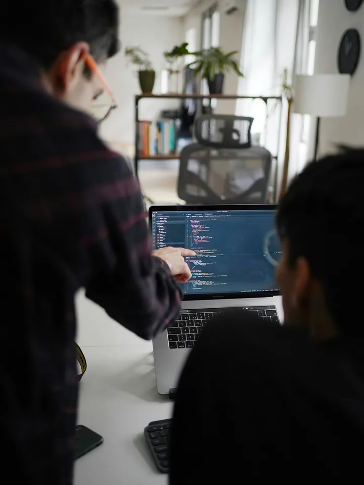 Developers collaborating and reviewing website code on a laptop